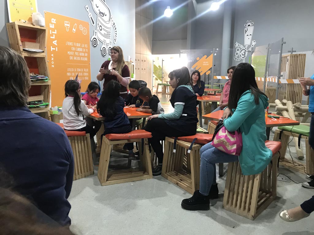 niños y niñas sentados en mesa didactica